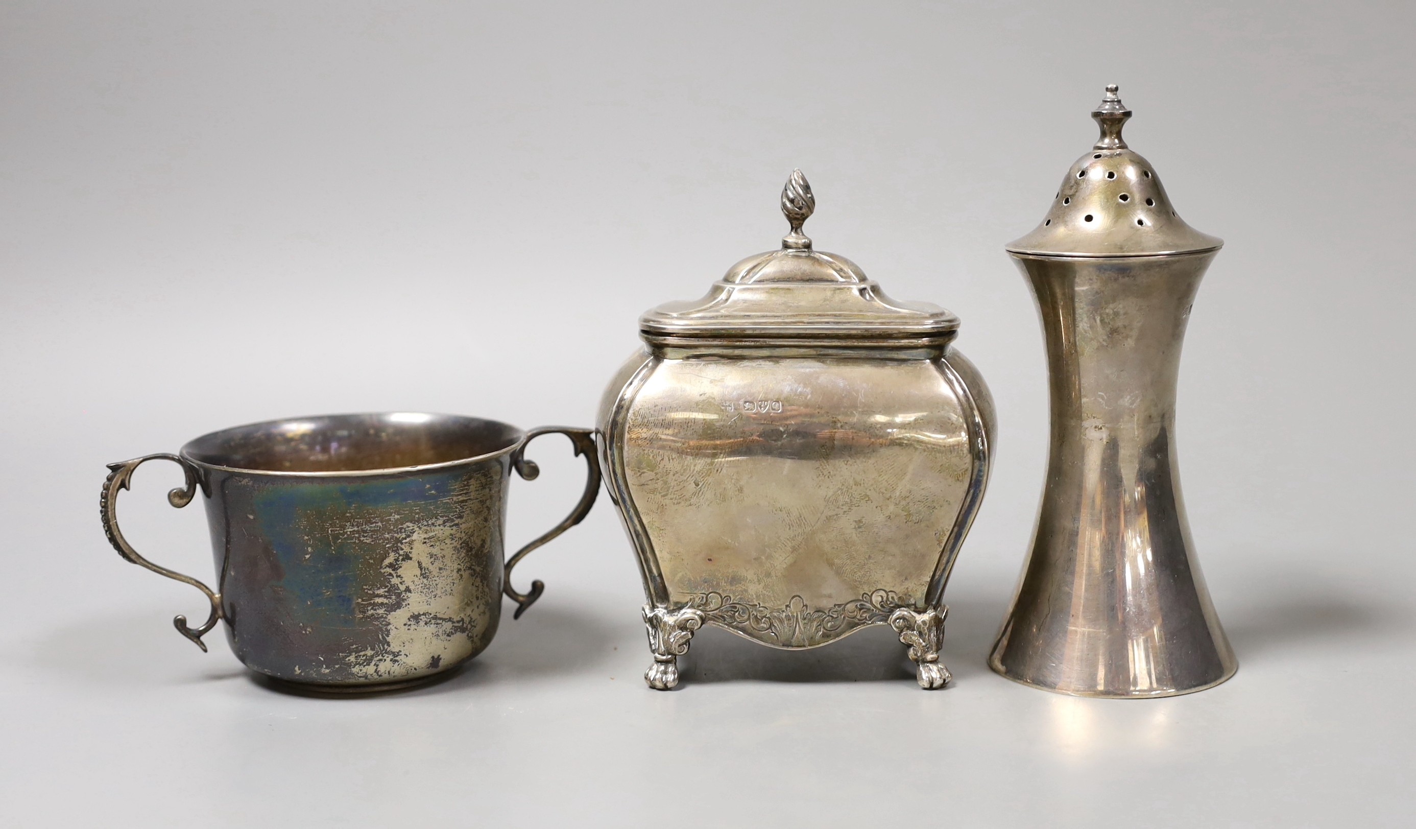 A late Victorian silver bombe shaped tea caddy, Nathan & Hayes, Chester, 1899, height 12.7cm, a later silver waisted sugar caster and a George V silver porringer, 15oz.